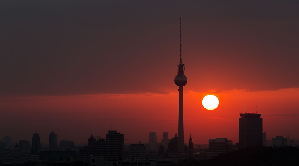 A city skyline at sunset with a prominent tower silhouetted against the sky.