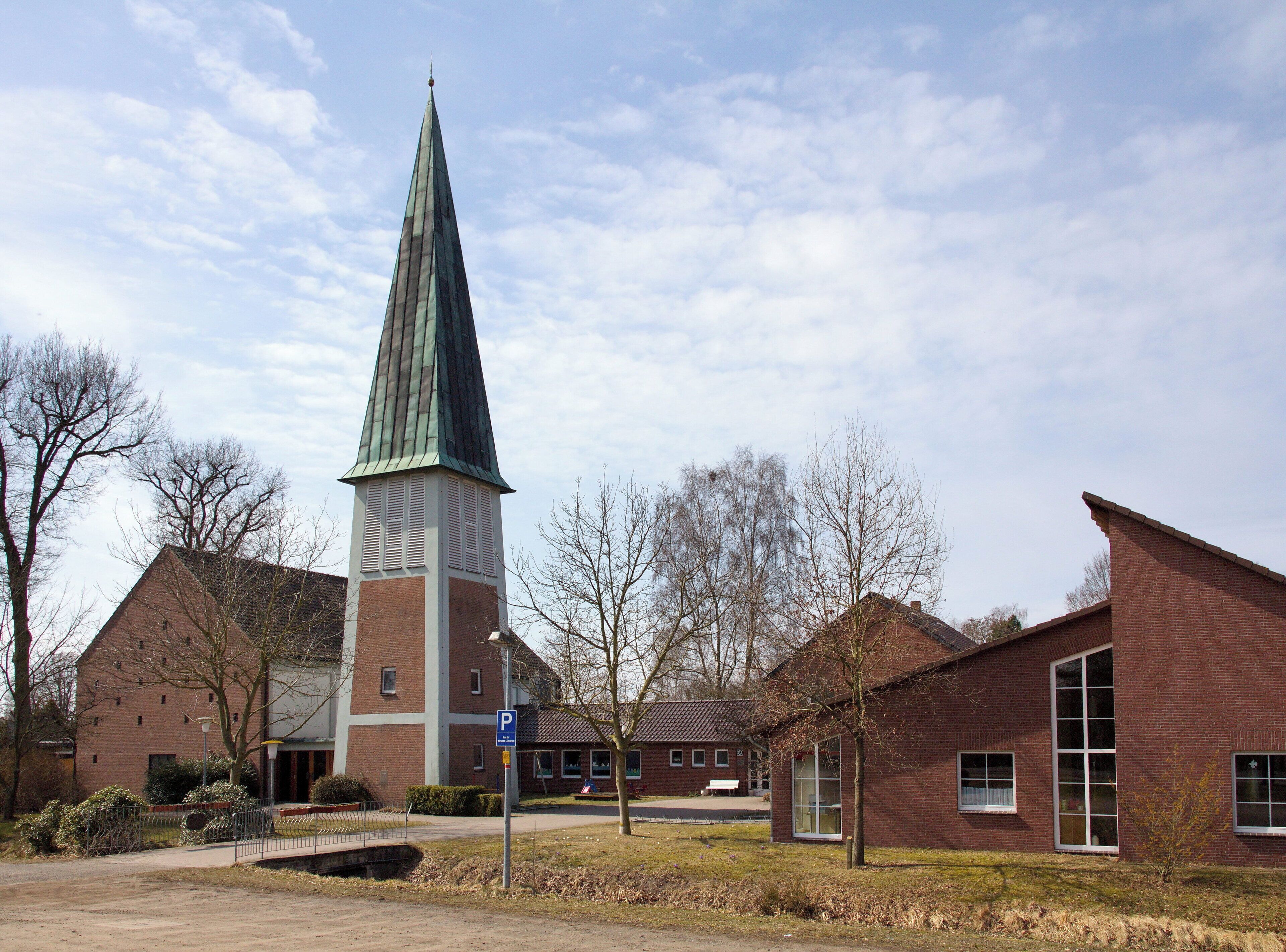 A church with a tall spire, brick buildings, and leafless trees.