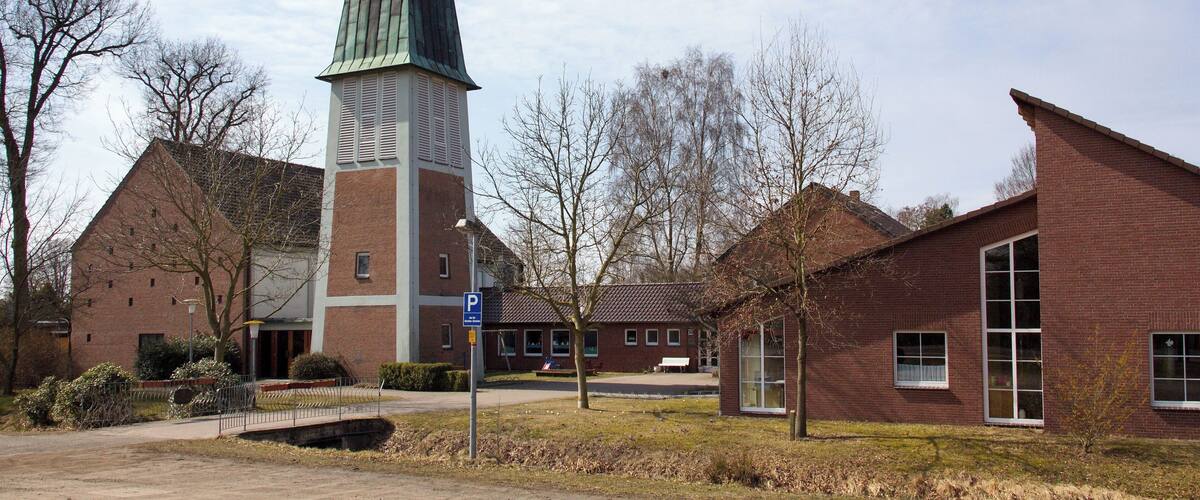 A church with a tall spire, brick buildings, and leafless trees.