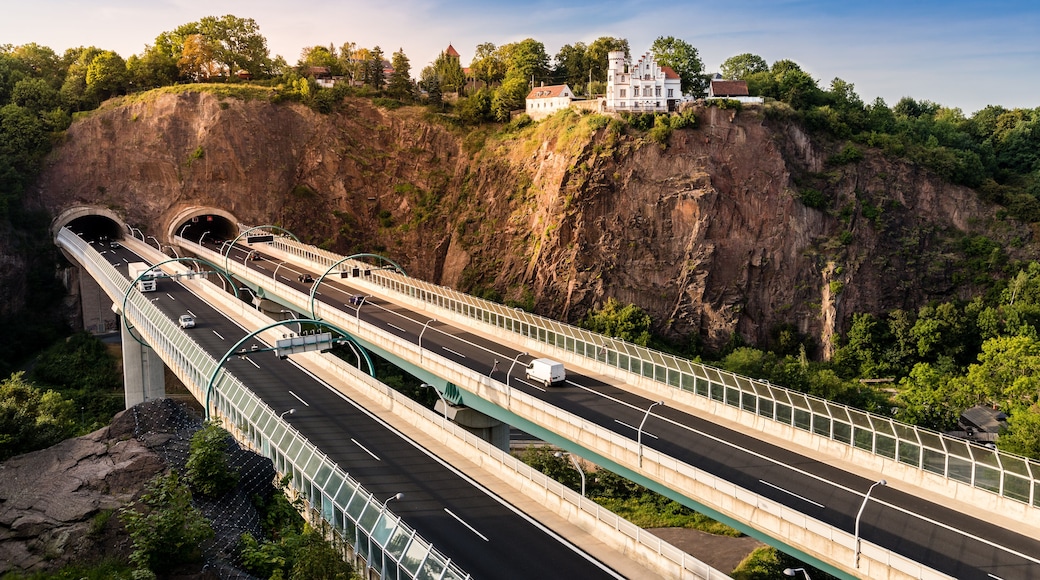 A multi-level highway bridge with vehicles, a tunnel entrance, and a castle on a cliff.