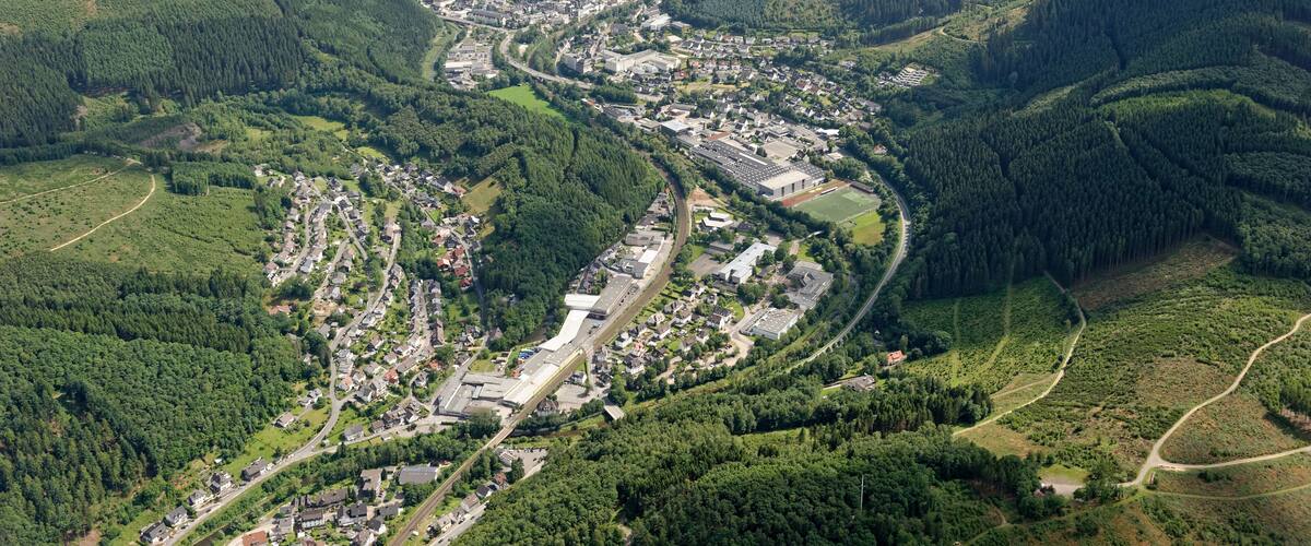 An aerial view of a town nestled in a valley with dense forests and rolling hills.