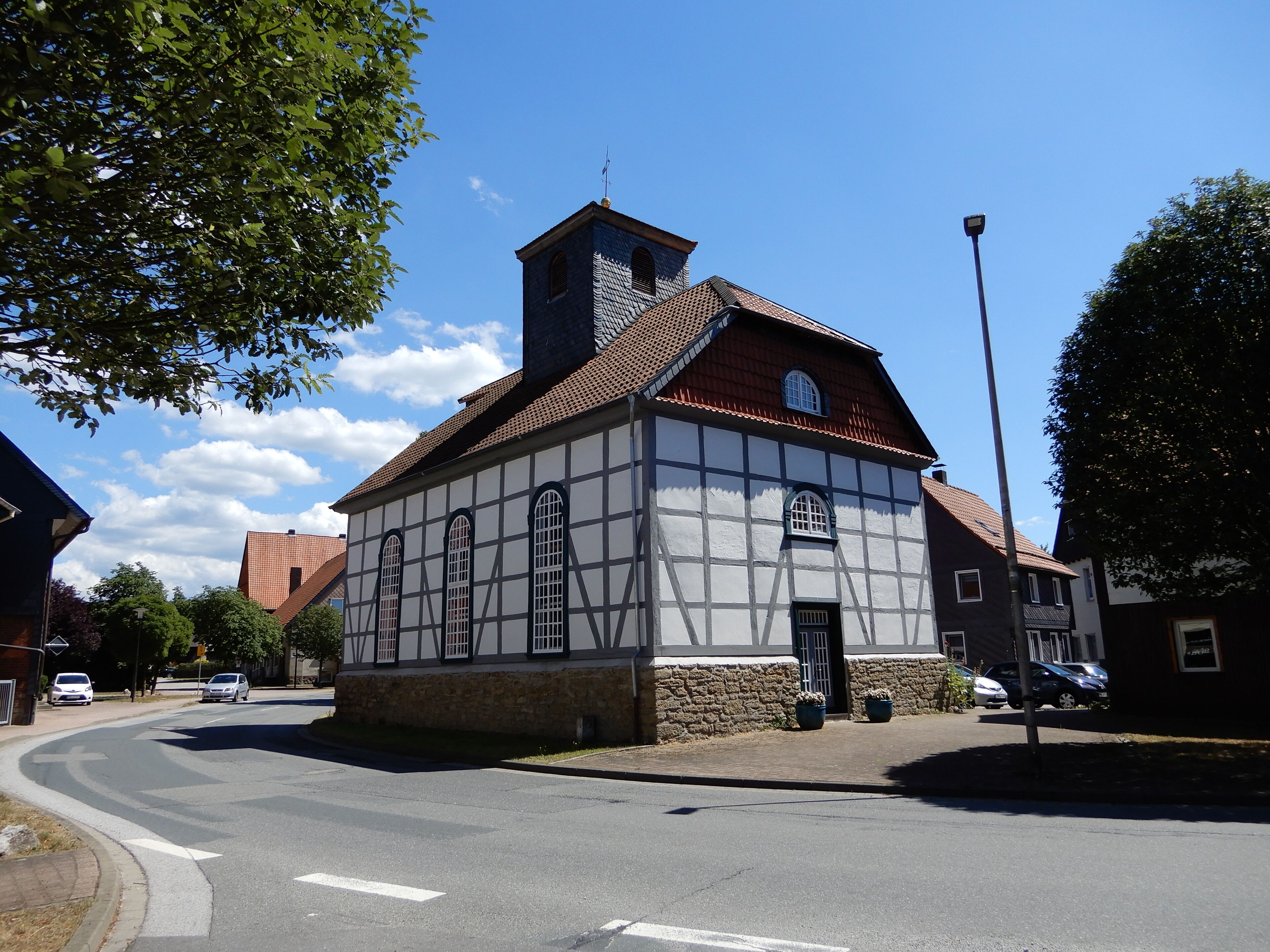 A traditional half-timbered building with a steeply pitched roof and a small tower.