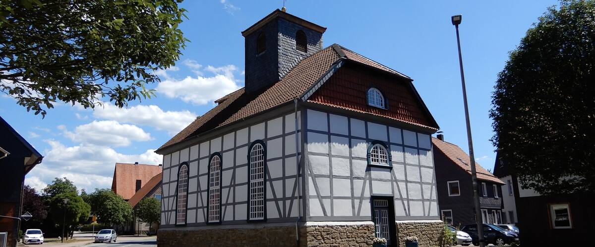 A traditional half-timbered building with a steeply pitched roof and a small tower.