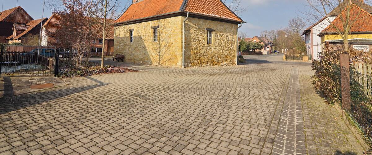 A cobblestone street lined with stone houses and a clear blue sky.