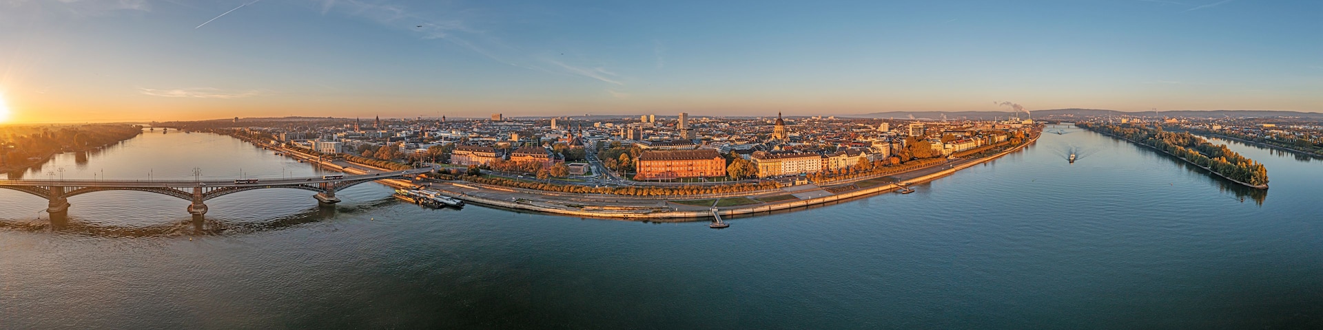 Eine Flusslandschaft mit einer markanten Brücke und einem imposanten historischen Gebäude in der Mitte.