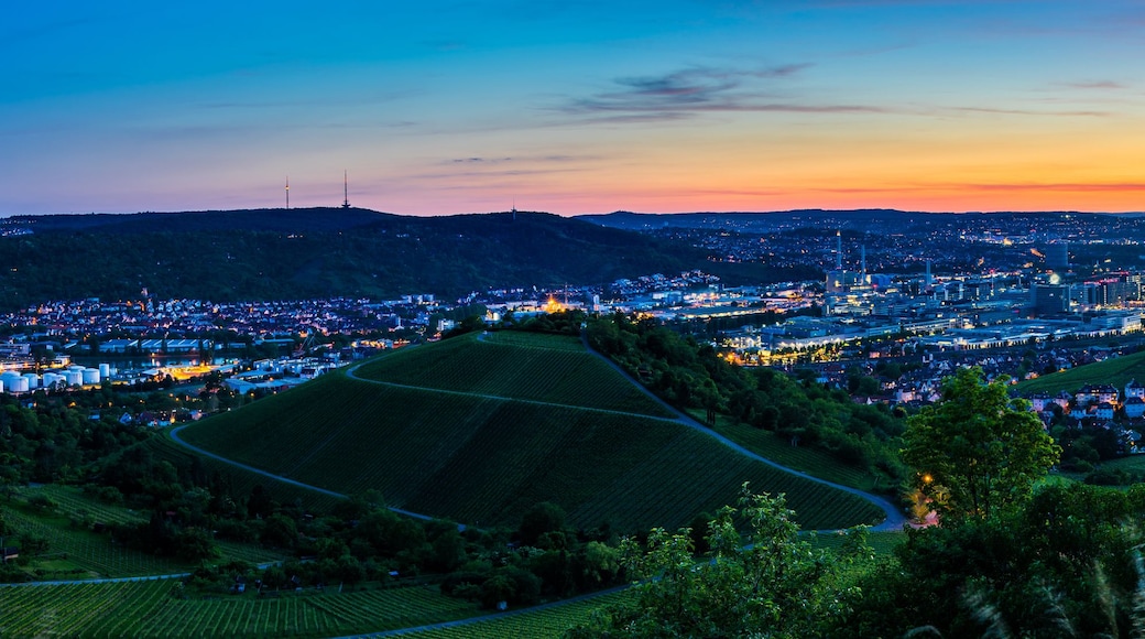 A cityscape at dusk with rolling hills and a river.