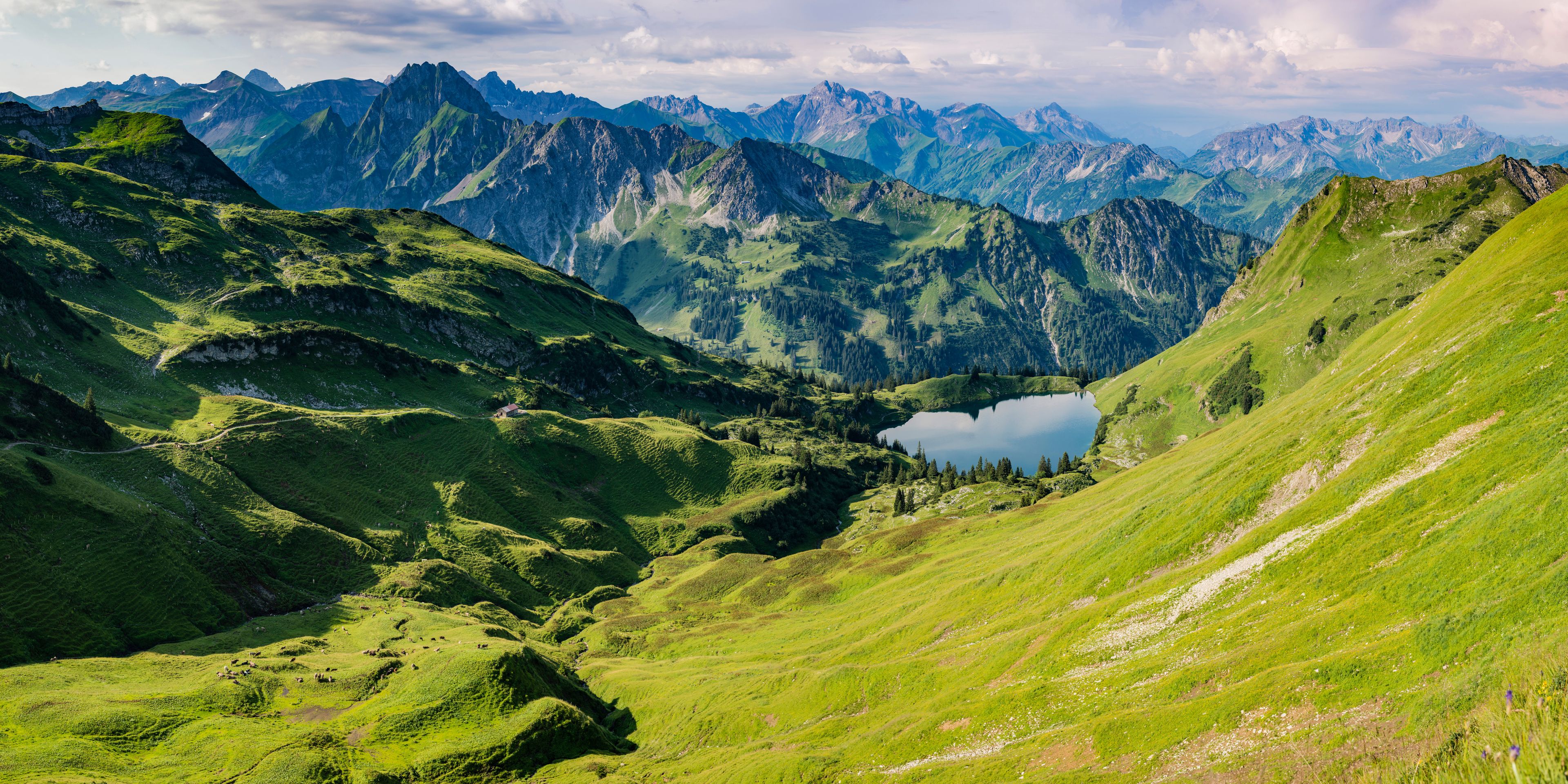 A mountainous landscape with a lake nestled in a valley, surrounded by steep cliffs and lush greenery.