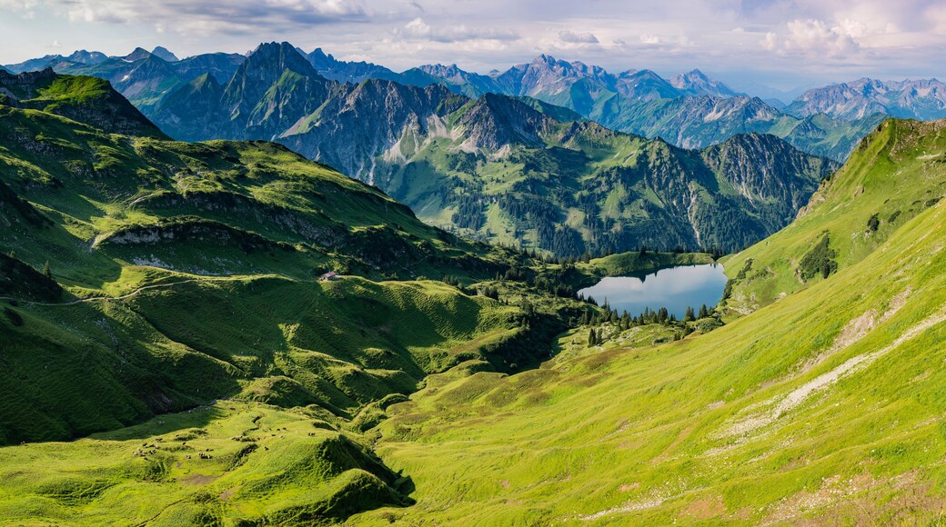 A mountainous landscape with a lake nestled in a valley, surrounded by steep cliffs and lush greenery.