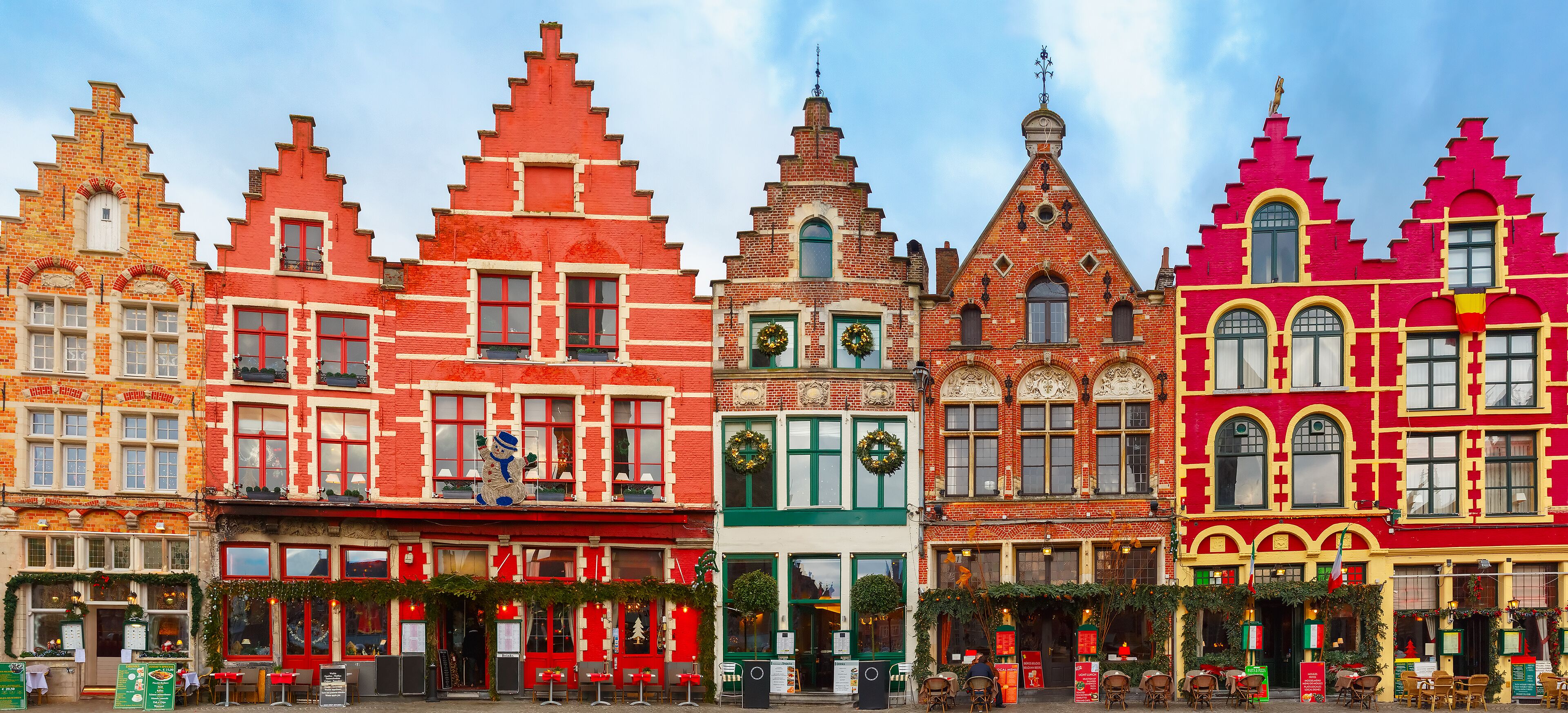 A row of colorful, historic buildings with distinctive architectural styles and festive decorations.