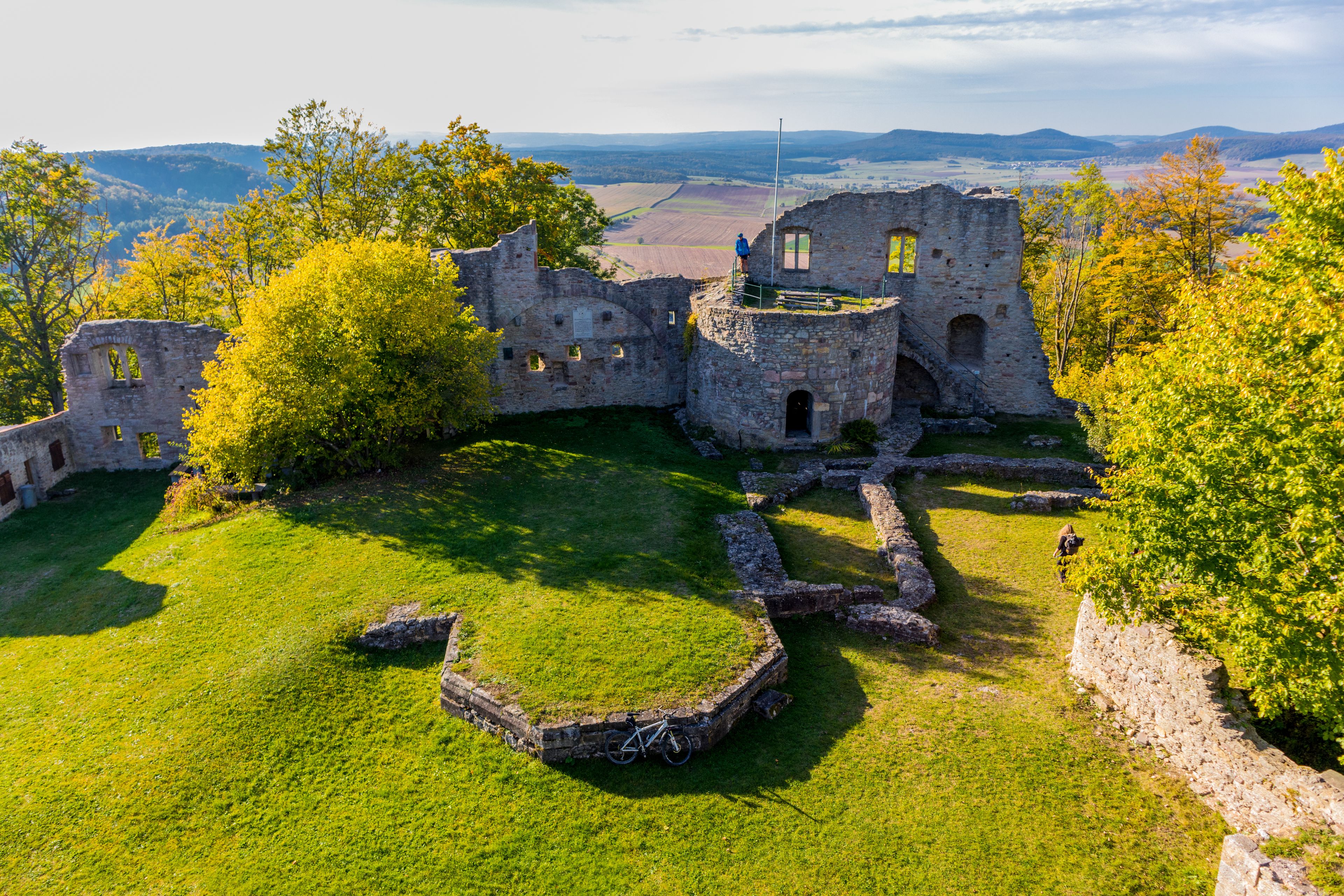 A historic stone castle ruins surrounded by lush green grass and trees.