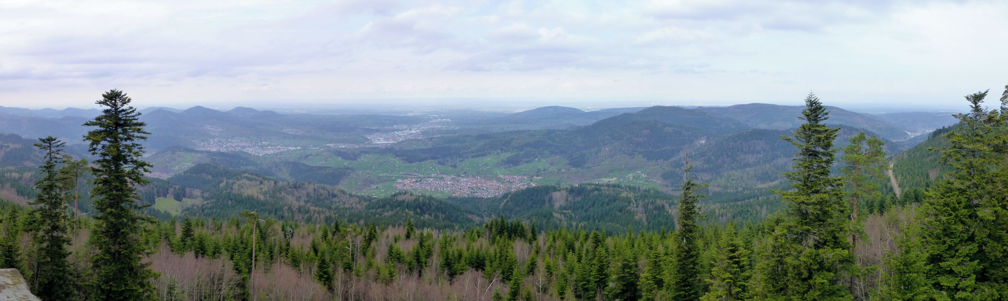 A mountainous landscape with dense forests and a small town nestled in the valley.