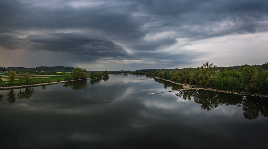 Un río que refleja un cielo tormentoso, rodeado de campos y árboles.