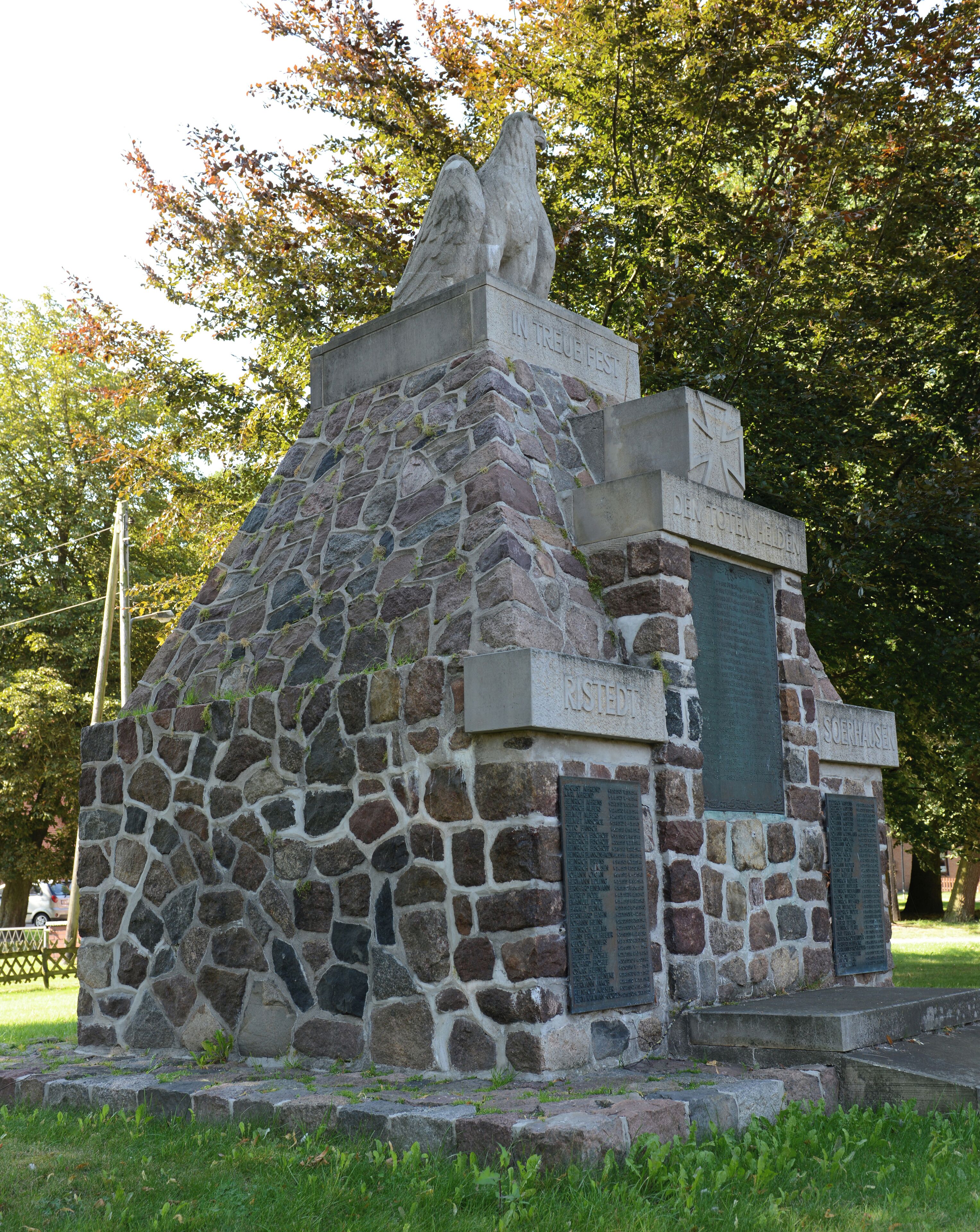 A stone monument with inscriptions and a statue of two figures.