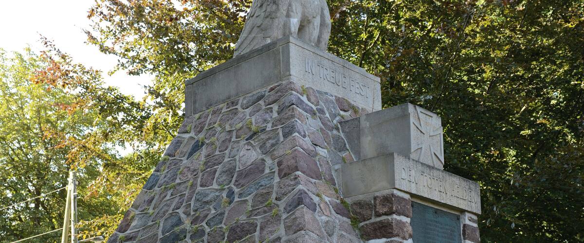 A stone monument with inscriptions and a statue of two figures.