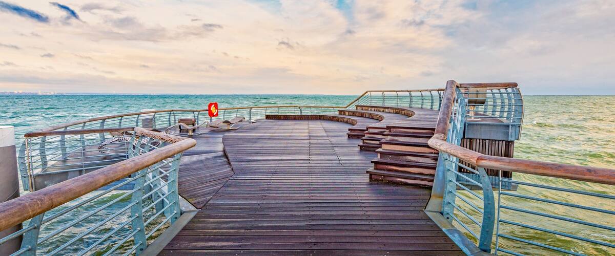 A wooden boardwalk with metal railings leading to a beach.