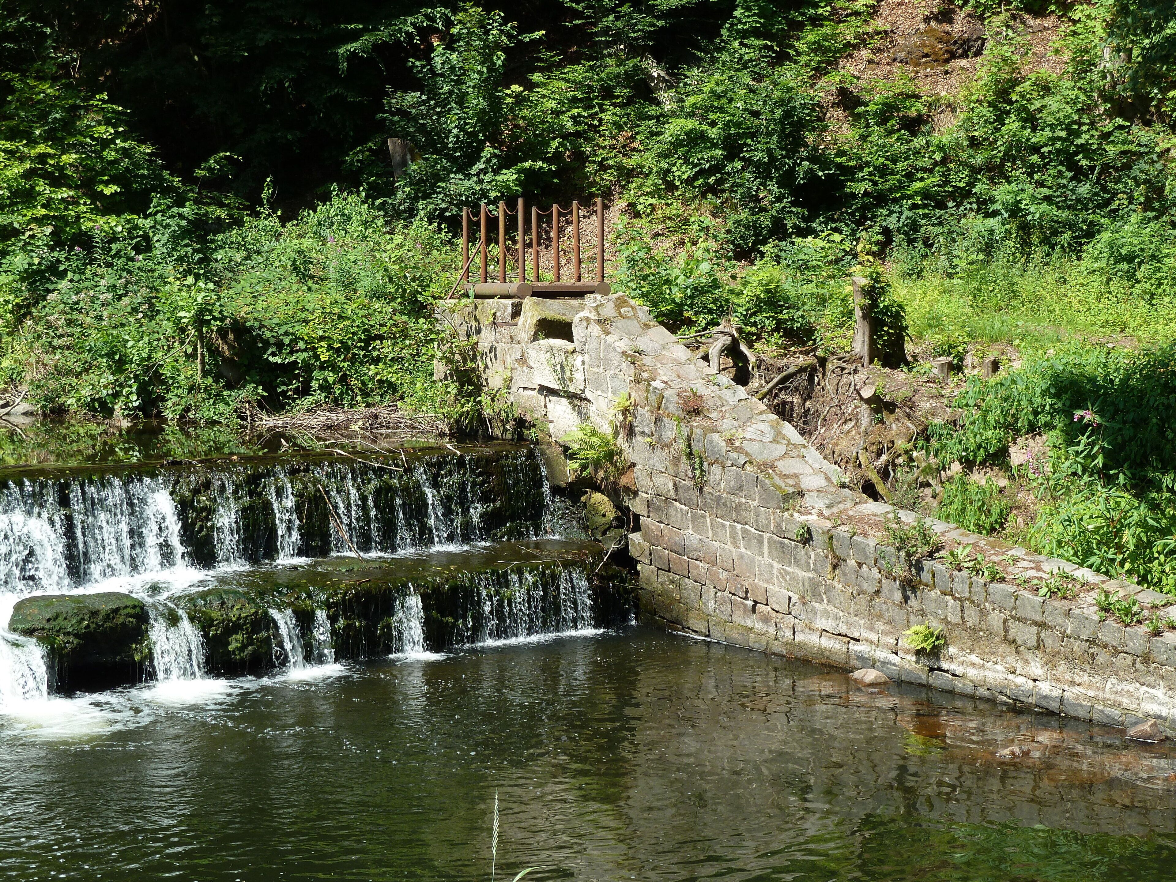 Picture shows the former inlet and an abandoned floodgate of the mill race from river Weisseritz to the nearby roller mill. The installation will be taken away in November 2017. After the floods of 2002 and 2013 the river bank gets hard-armoured with large rocks for preventing erosion when the river becomes a torrent and for maintaining the flood conveyance capability in the V-shaped valley. When further existing, the inlet would spoil the coherence of the river bank.