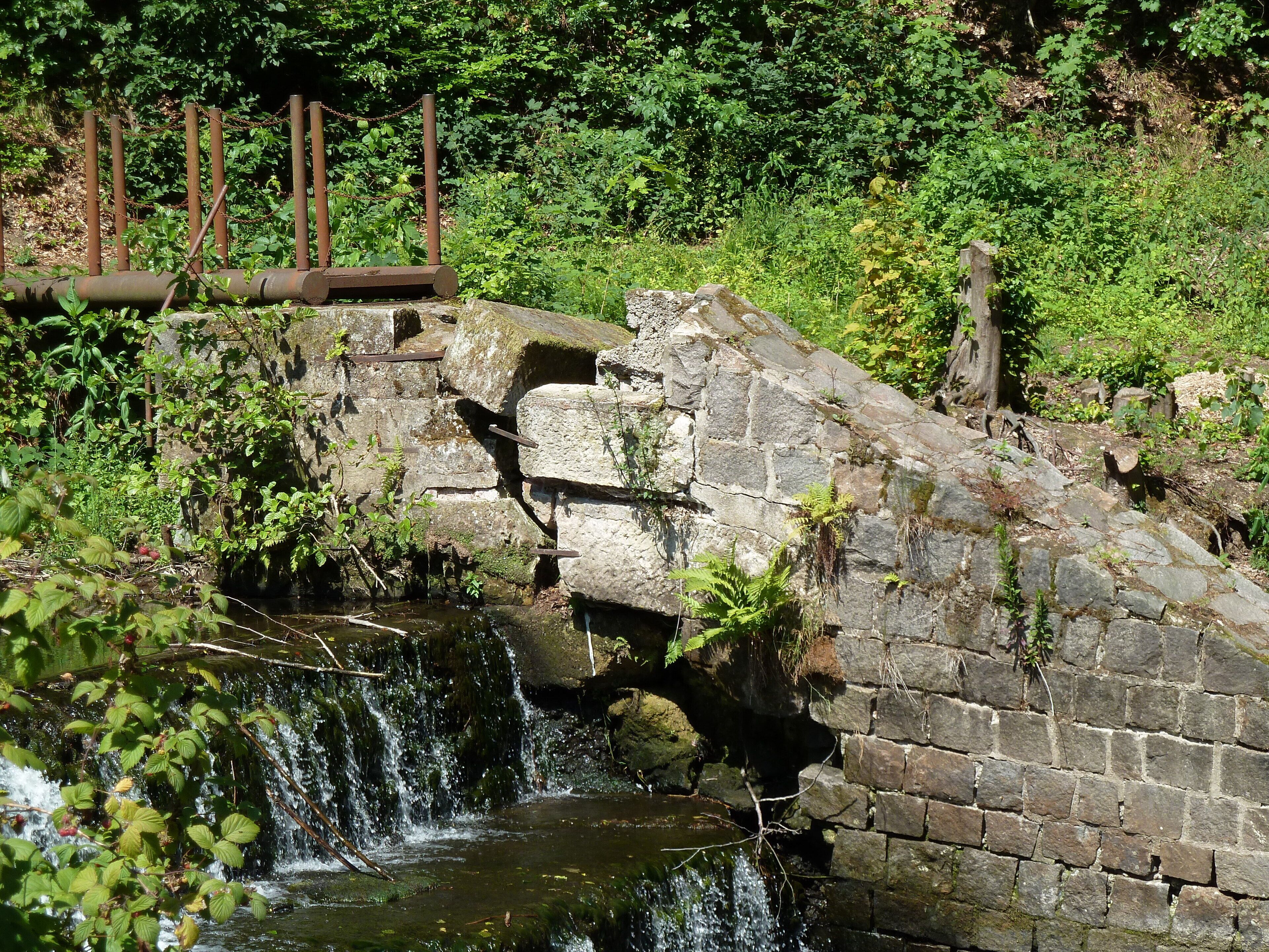Picture shows the former inlet and an abandoned floodgate of the mill race from river Weisseritz to the nearby roller mill. The installation will be taken away in November 2017. After the floods of 2002 and 2013 the river bank gets hard-armoured with large rocks for preventing erosion when the river becomes a torrent and for maintaining the flood conveyance capability in the V-shaped valley. When further existing, the inlet would spoil the coherence of the river bank.