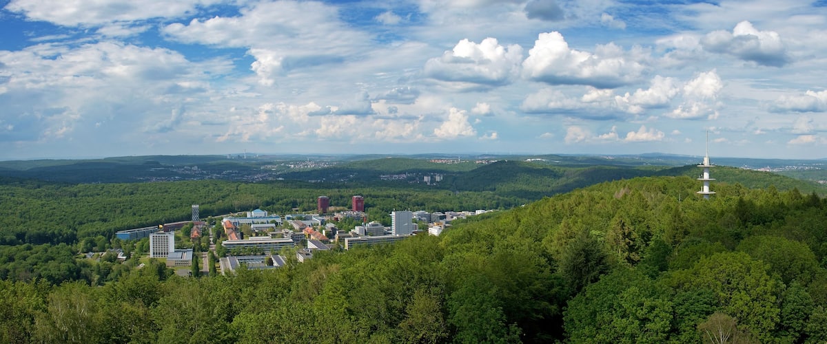 A town nestled in a valley with a prominent white tower on a hill.