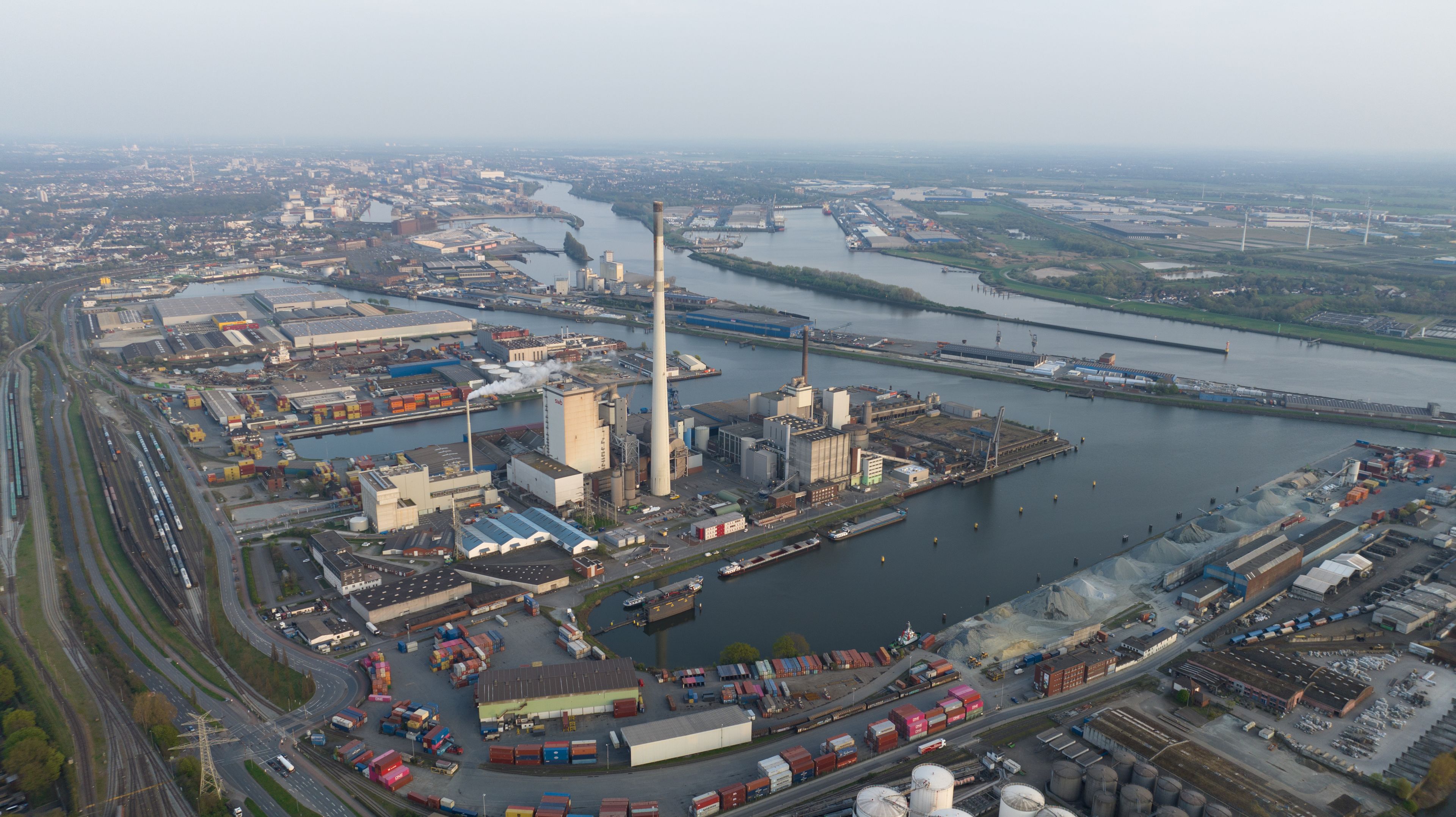 An industrial port with shipping containers, a large cargo ship, and a river.