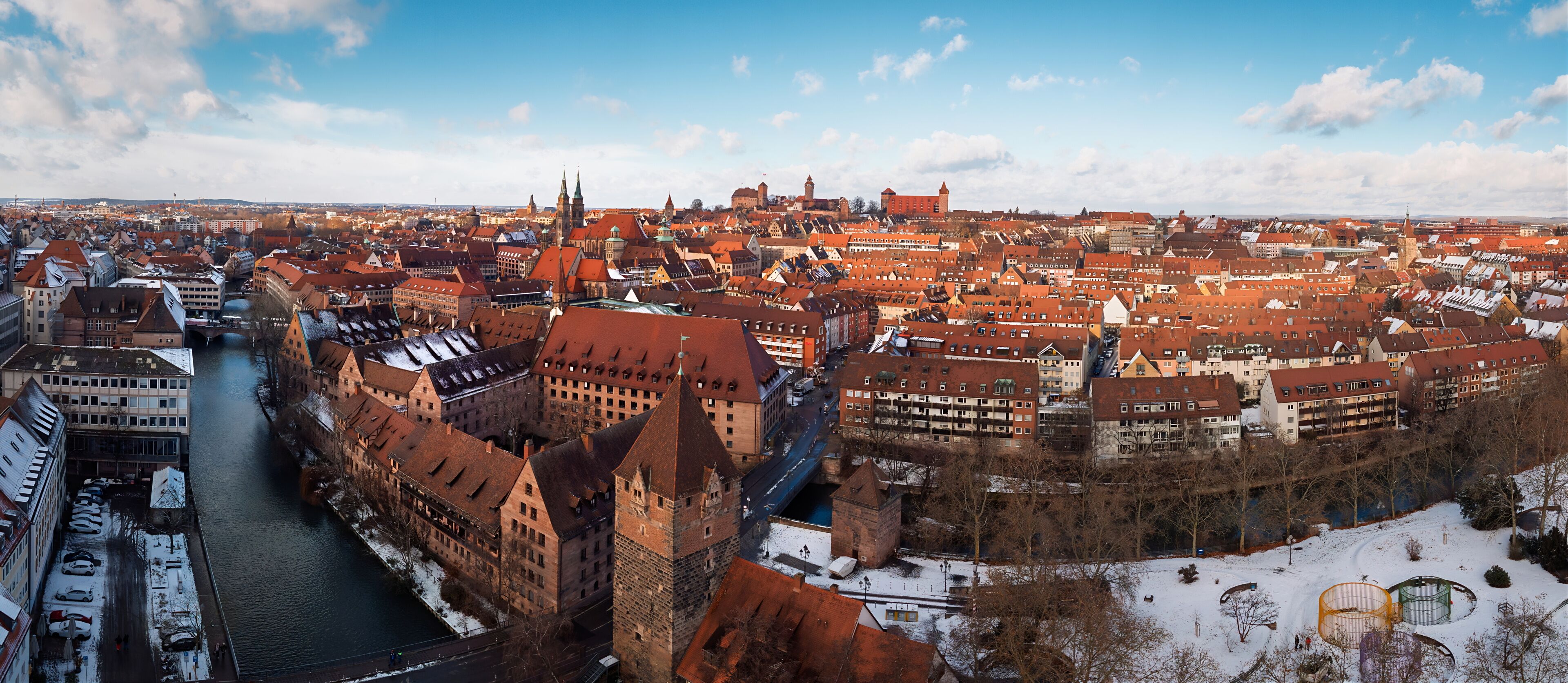 Aerial view of the snow-dusted roofs and the flowing Pegnitz River under a crisp winter sky, Nuremberg, Germany.