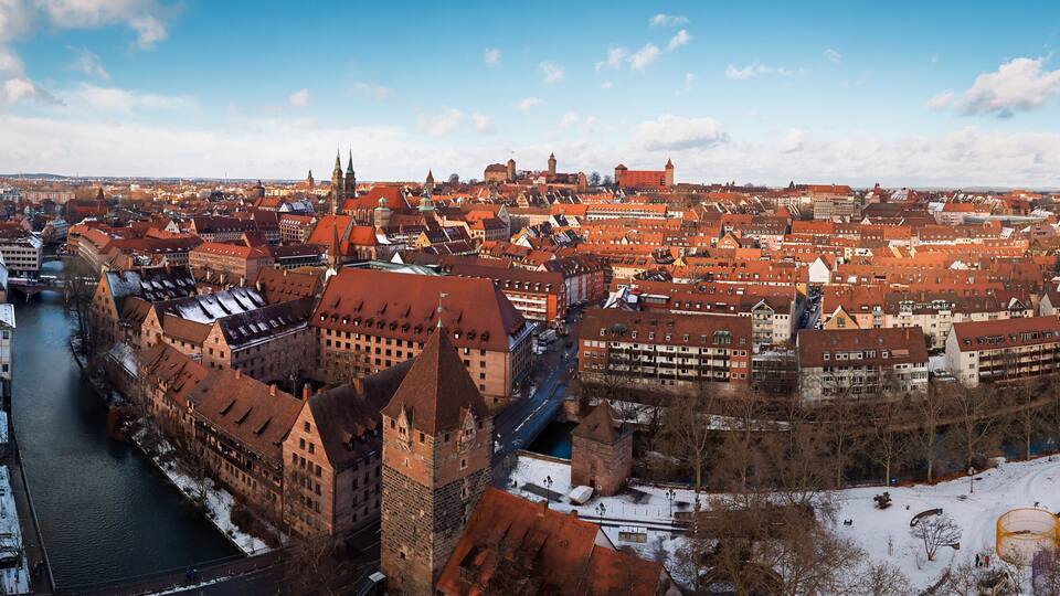 Aerial view of the snow-dusted roofs and the flowing Pegnitz River under a crisp winter sky, Nuremberg, Germany.