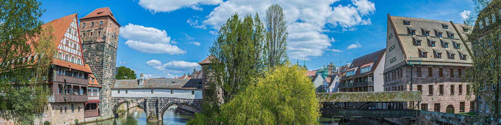 Nuremberg, Bavaria, Germany - April 30, 2023: View from Maxbrücke bridge towards the Hangman's Bridge built in1595, Henkersbrücke bridge, Henkerhaus Museum and Wasserturm, over Pegnitz river.