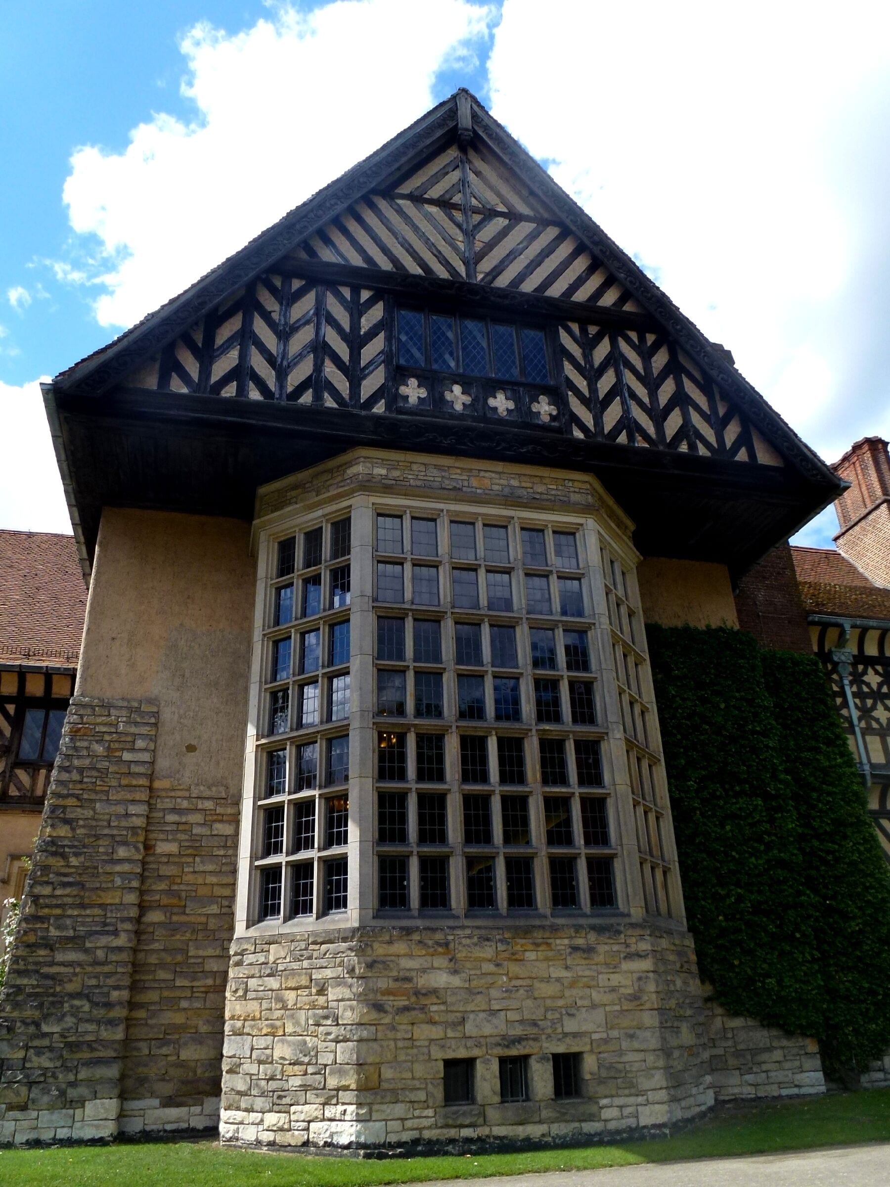 Un edificio histórico con techo de estilo Tudor, ventanas grandes y paredes de piedra.