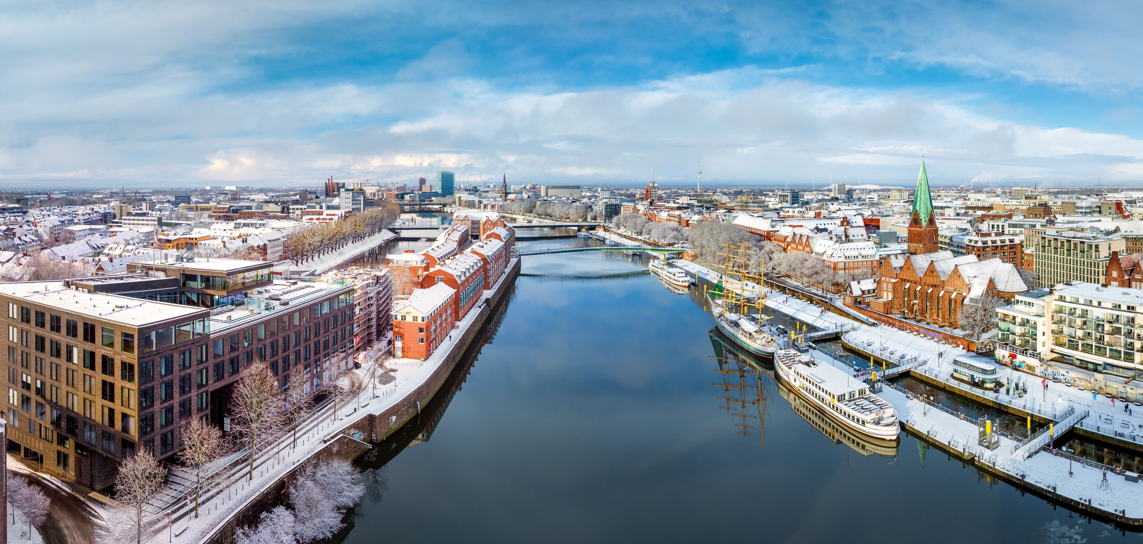 A river with buildings on both sides, a bridge, and a tower in the distance.