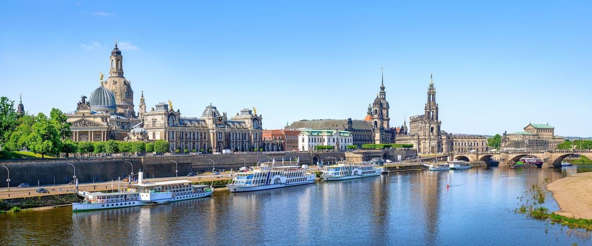 Ein Fluss mit Booten, einer Brücke und historischen Gebäuden am Ufer.