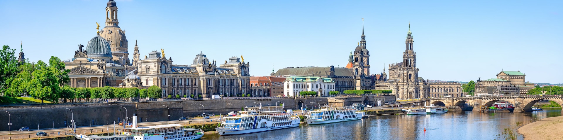 Ein Fluss mit Booten, einer Brücke und historischen Gebäuden am Ufer.