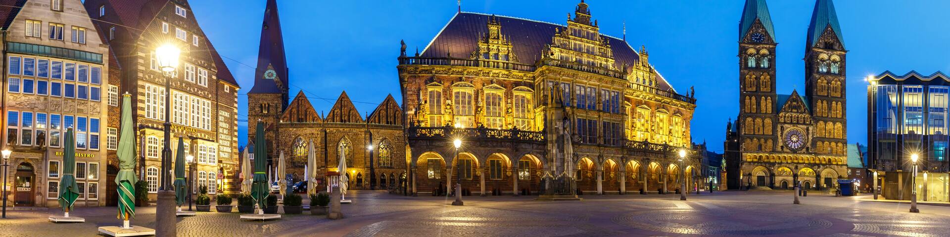 A historic building with ornate architecture and a clock tower, surrounded by cobblestone streets and other traditional buildings.