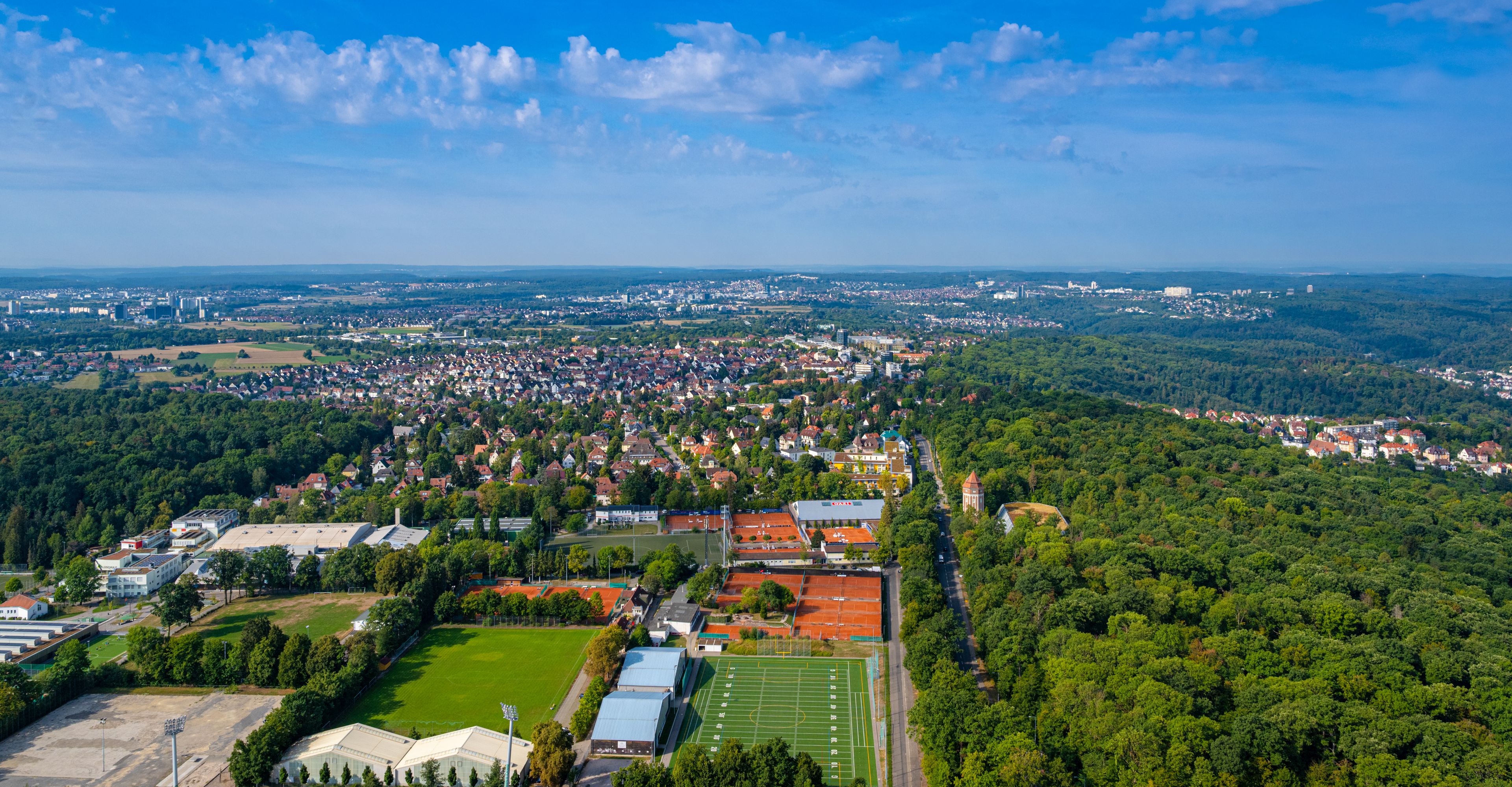 Un pueblo rodeado de bosques, con un campo de fútbol y edificios.