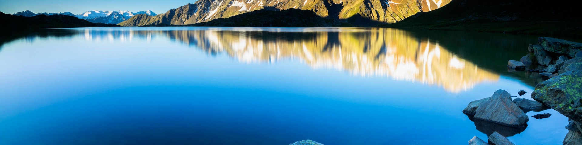 Cordilheira refletida em um lago calmo sob céu claro.