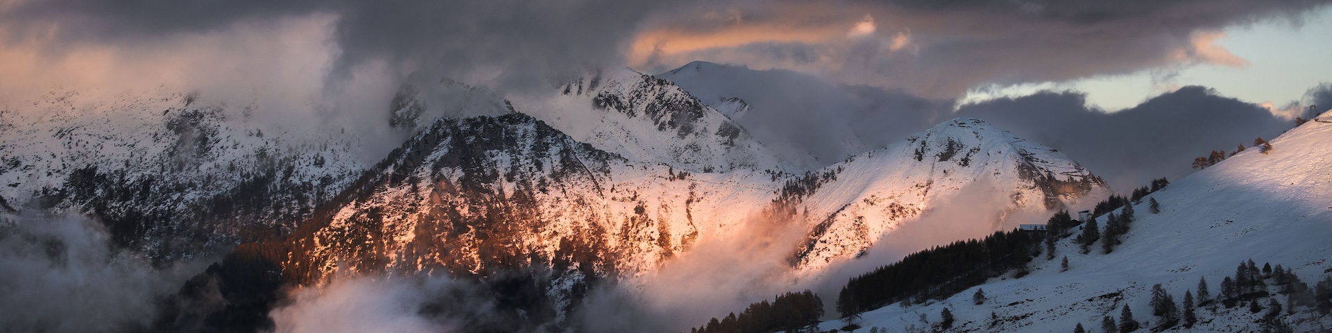 Montanhas cobertas de neve, um vale e um nascer do sol.