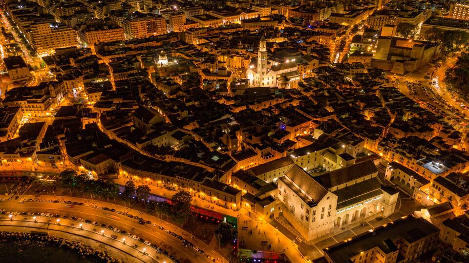 Luchtbeeld van een stad 's nachts, met verlichte gebouwen en straten.