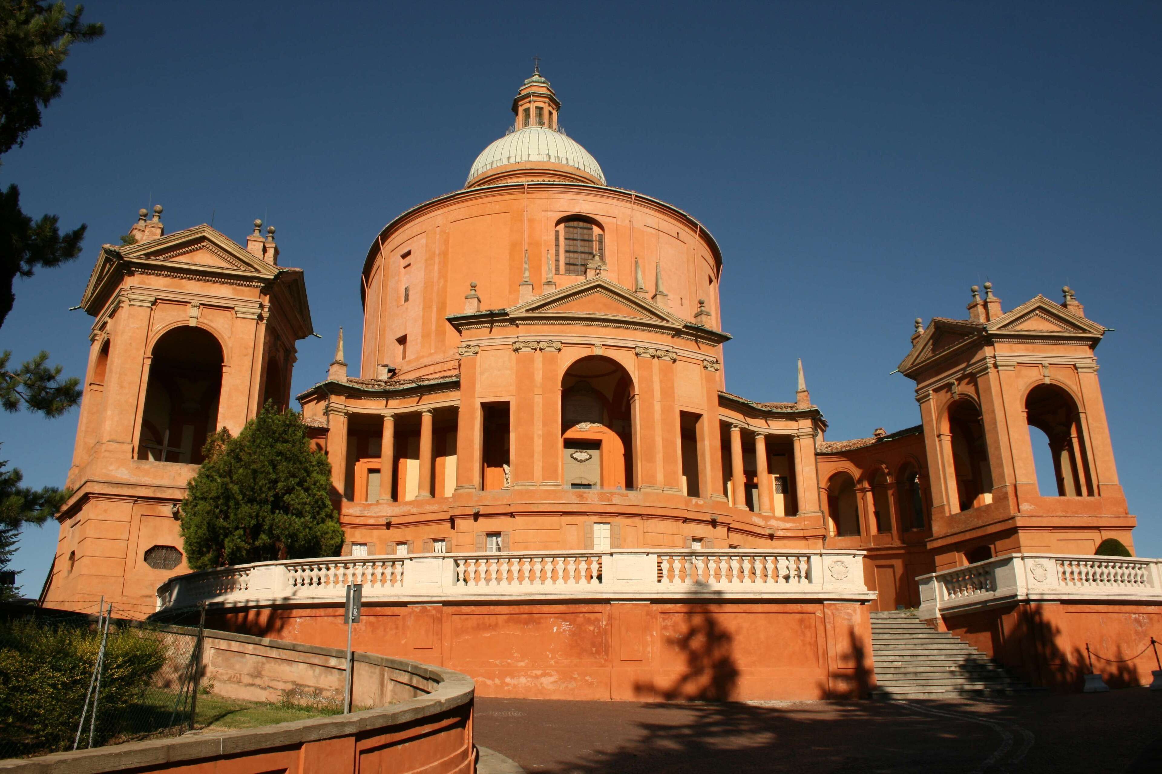 A large, domed building with arched windows and a central dome, surrounded by a fence and trees.