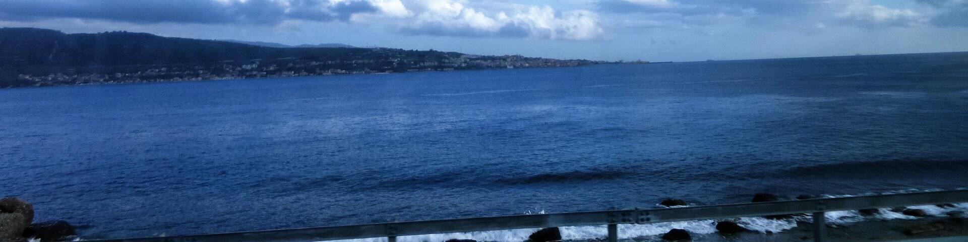A coastal landscape with a view of the sea and a distant shoreline.