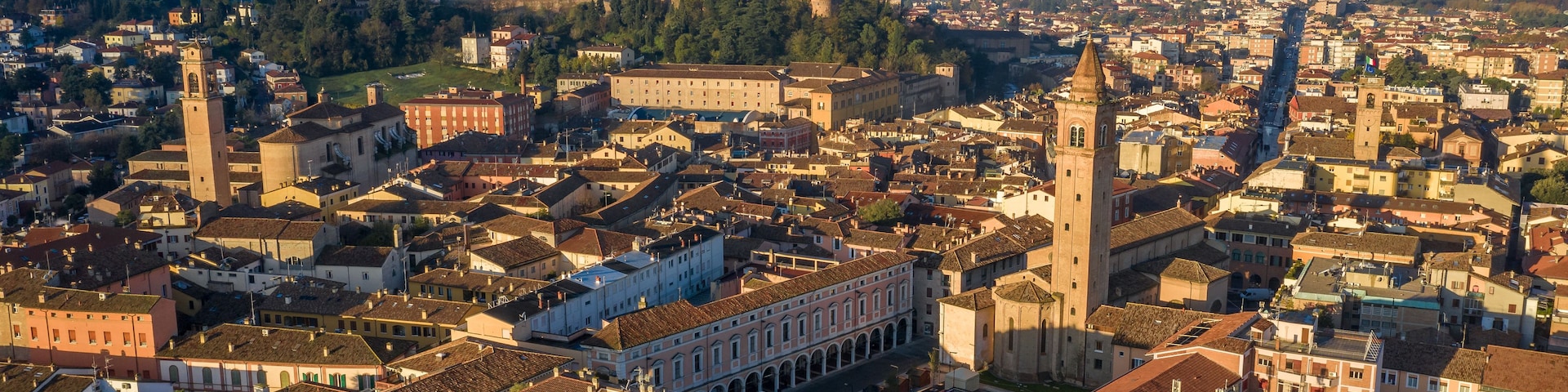 Vista panorámica de una ciudad histórica con arquitectura urbana densa, torres destacadas y colinas ondulantes al fondo.