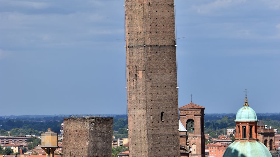 En el s.XII las familias ricas de esta ciudad mostraban su poder mediante la altura de sus torres. La ciudad medieval estaba repleta de estas torres a modo de rascacielos medievales. Varias de estas torres han llegado a nuestros días, siendo la Torre Asinelli y la Torre Garisenda las más famosas de ellas. Las dos torres están inclinadas y se han convertido en el símbolo de esta ciudad. La torre Asinelli es la más alta y mide 97,6 metros. Tiene una inclinación de 1,3 metros y dispone de un mirador en la parte superior. Para llegar a él hay que ascender 498 escalones. La torre Garisenda está más inclinada (3,2 metros) y mide 48 metros de altura. Su inclinación es tal que su altura tuvo que ser recortada en el s.XIV para evitar su derrumbe. Dante Alighieri hace referencia a ella en uno de los cantos del Infierno en la Divina Comedia.
