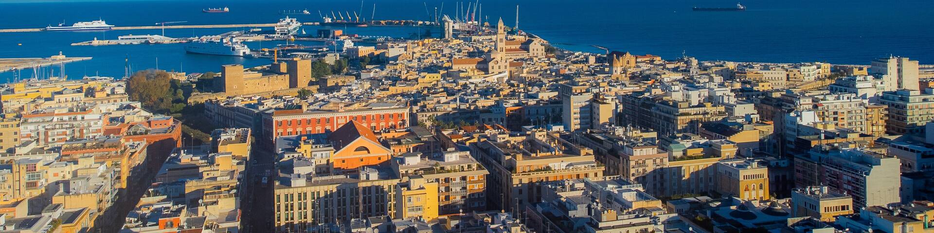 A coastal cityscape with a prominent church, a harbor with ships, and a clear blue sky.