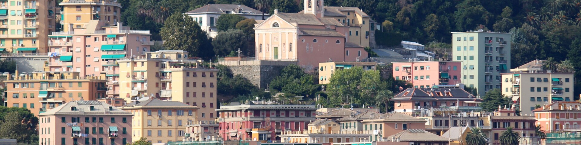 Un paisaje costero con edificios coloridos, una playa y una colina con una iglesia.