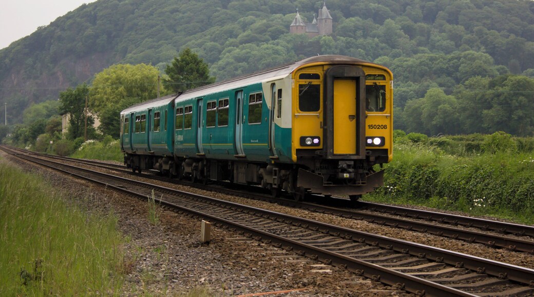 Class 150 Sprinter DMU 150208 is seen approaching the level crossing at Gelynis Farm - between Taffs Well and Radyr, with Arriva Trains Wales' 2F76 1808 Merthyr Tydfil to Cardiff Central service on 4th June 2016. In the background can be seen Castell Coch, nestled among the trees above north Cardiff.