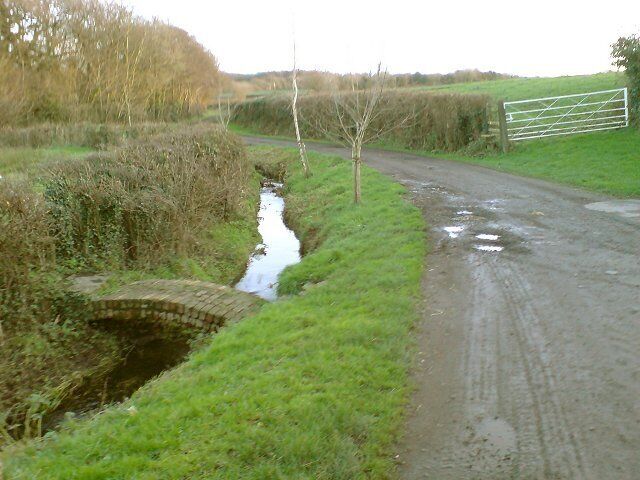 A small footbridge over a brook Near to Grove Farm, this small footbridge forms part of a public footpath that roams through farm fields in this area.