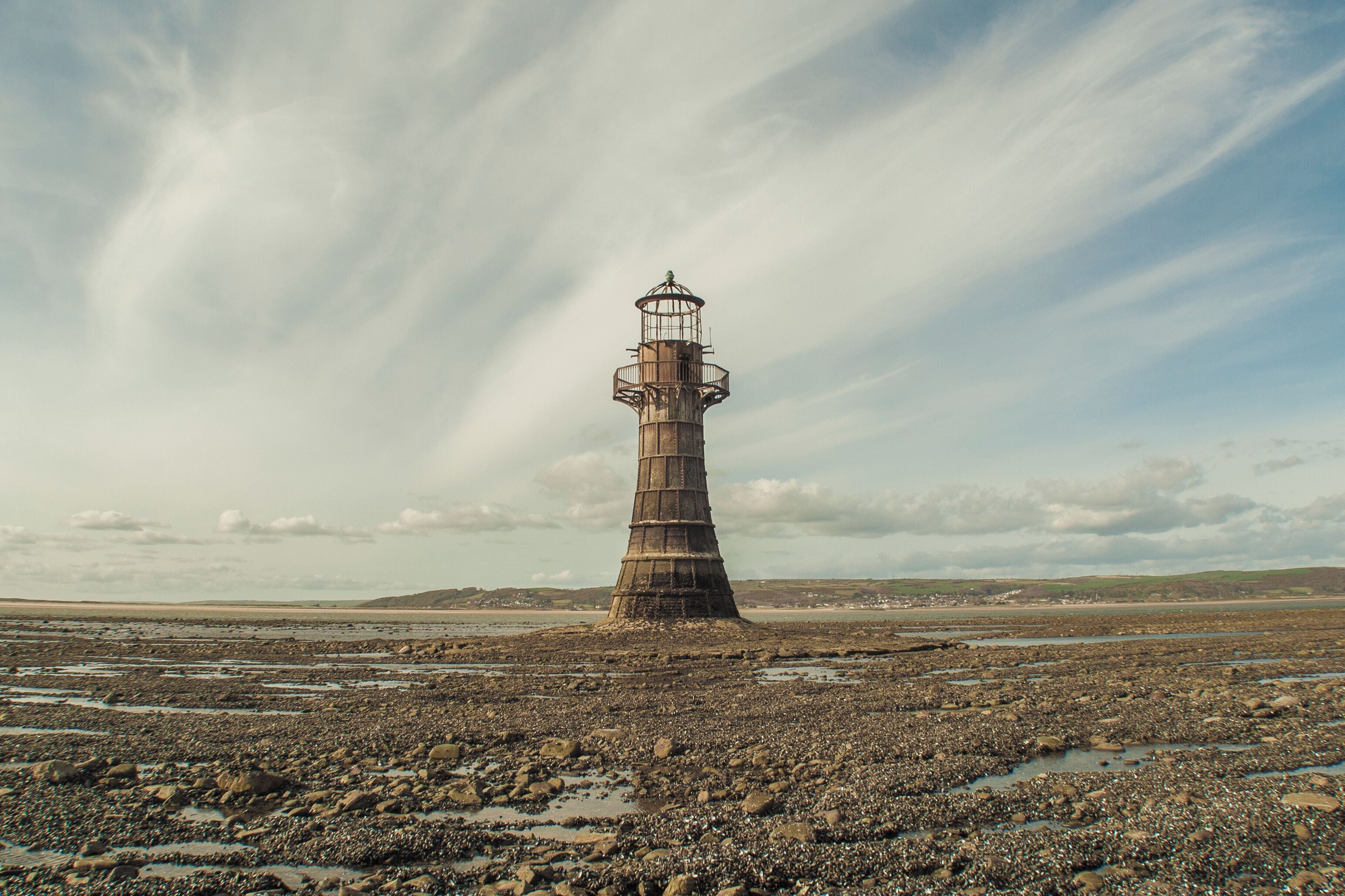 Un phare sur une côte rocheuse, sous un ciel nuageux.