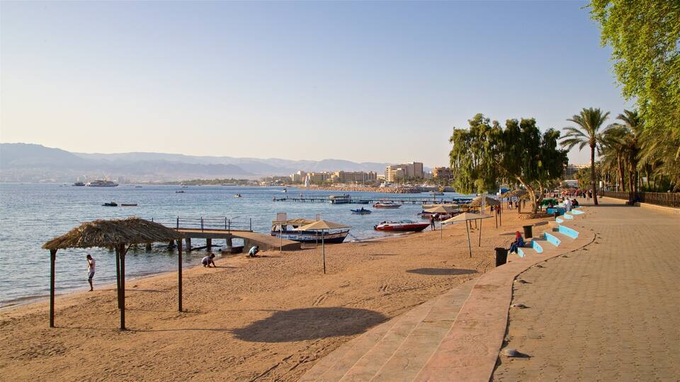 A beach with boats, a thatched-roof structure, palm trees, and a cityscape in the background.