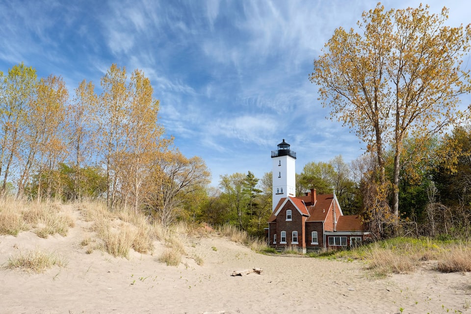 A lighthouse, a brick building, and autumn trees.