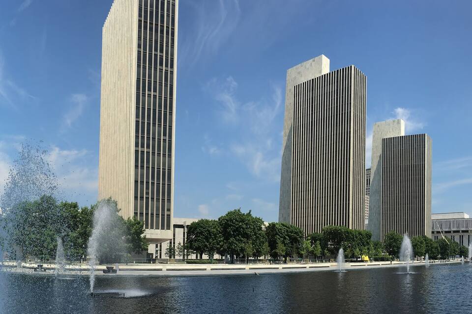 Un paysage urbain moderne avec de hauts immeubles et une fontaine centrale.