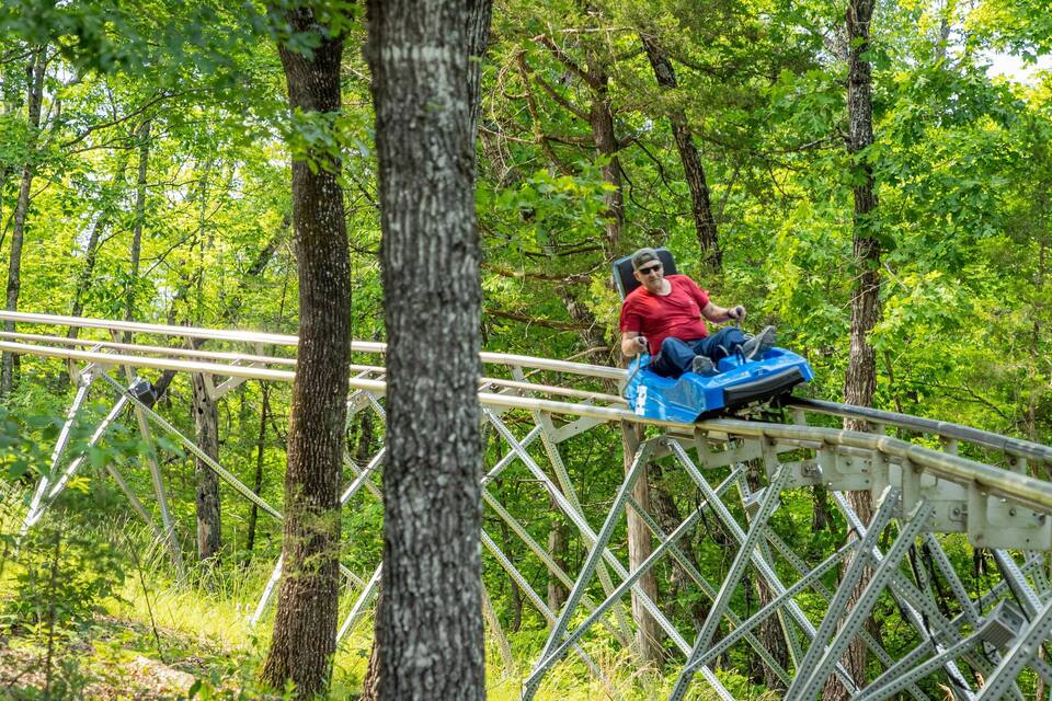 Una persona en un tobogán acuático azul en un bosque.