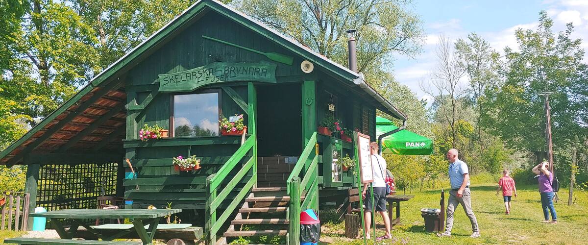 A green wooden cabin with a sign reading "Skelarska - Brynara" and a green umbrella.