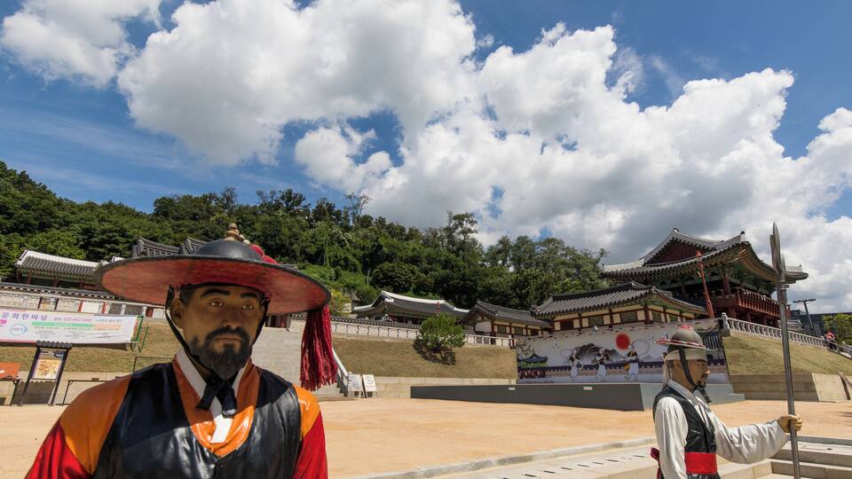 A traditional Korean gate and a statue of a historical figure.